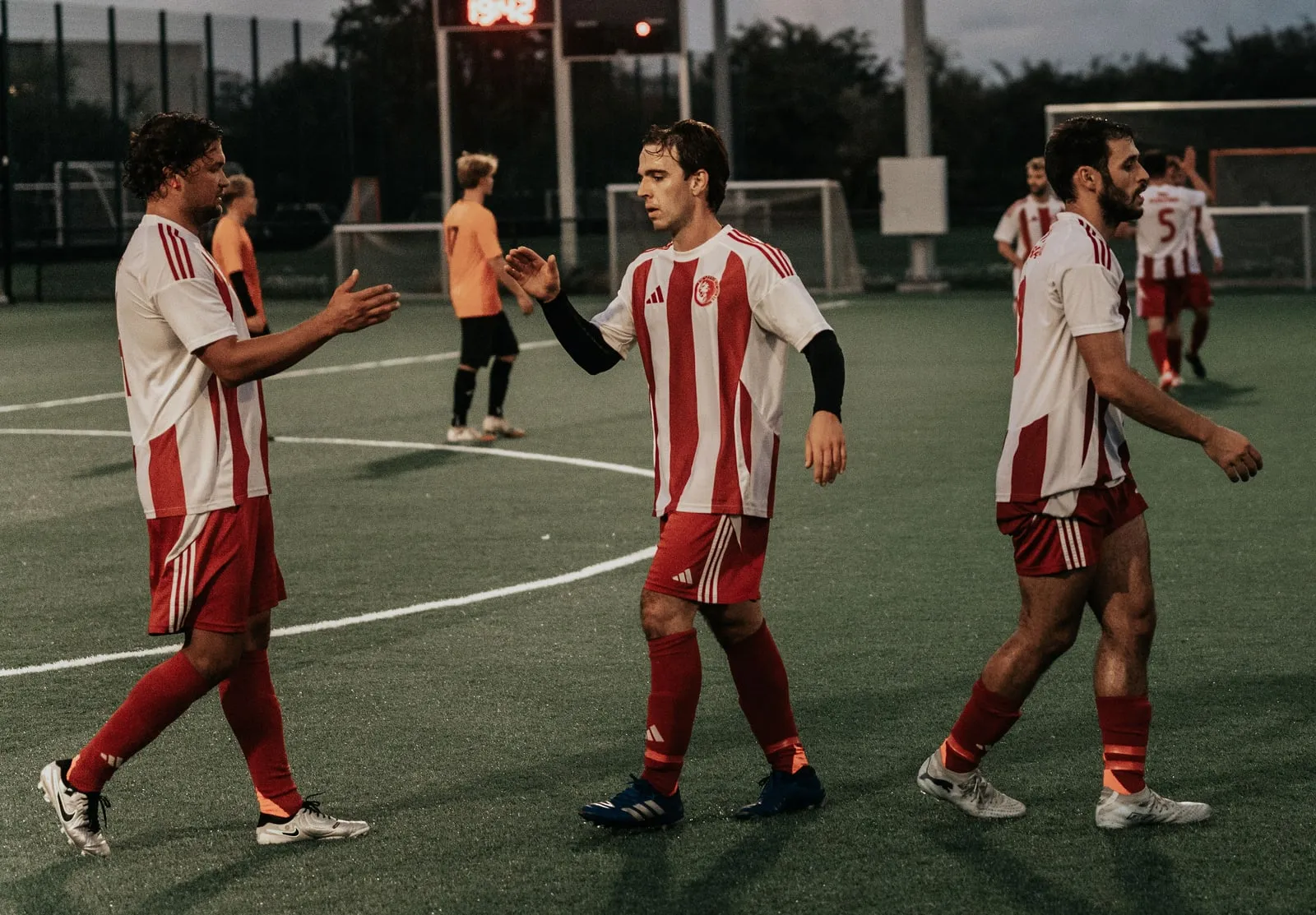 Two teammates reach out to shake hands on the pitch
