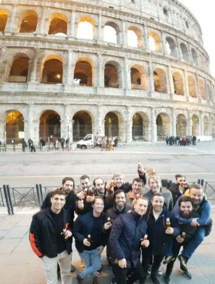 The group raises their drinks in front of the Colosseum in Rome